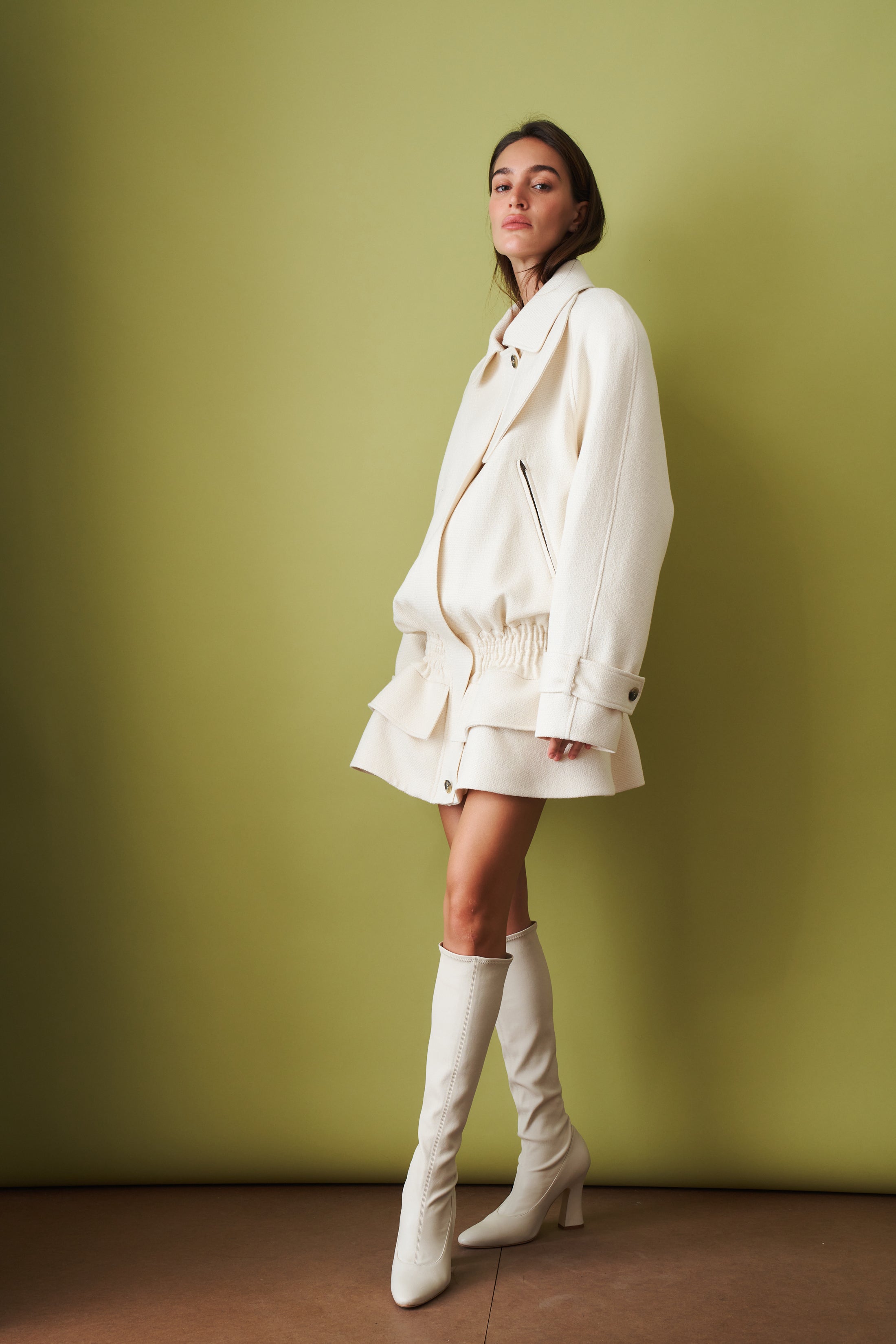 Ecru coat by THE MANNEI, stylish jacket displayed on a hanger with detailed fabric and classic design.