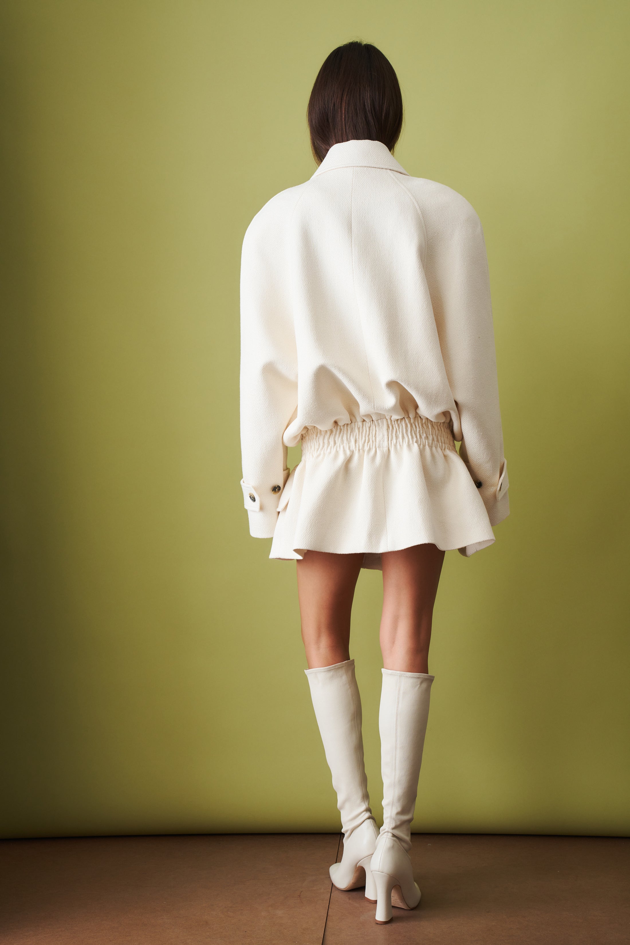 Ecru coat by THE MANNEI featuring a stylish jacket with a tailored fit and classic design, shown on a hanger.