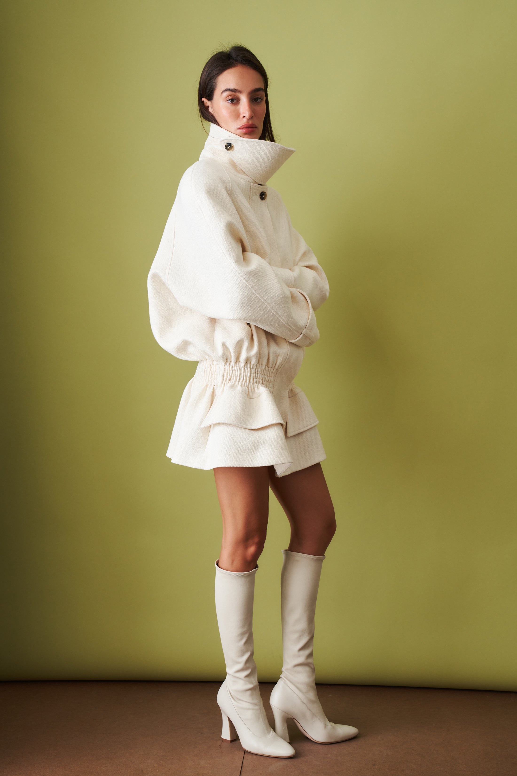 Ecru coat by THE MANNEI, stylish jacket with a tailored fit, displayed on a hanger with detailed fabric texture.