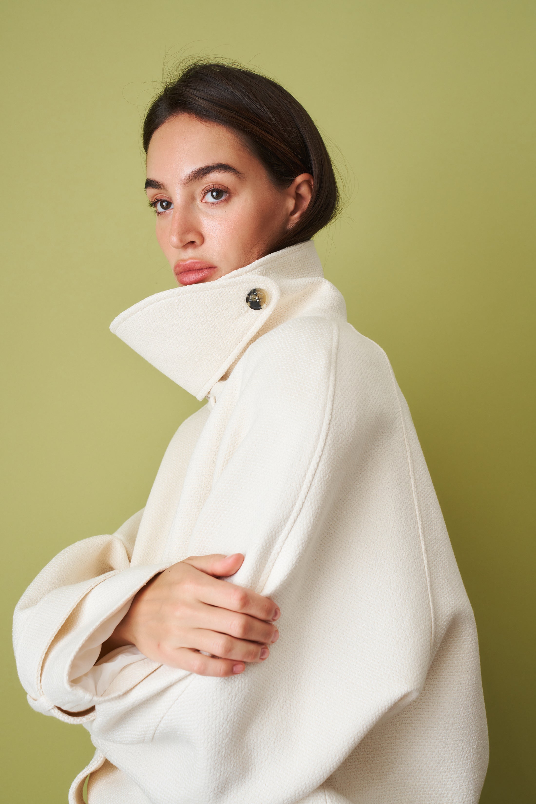 Ecru coat by THE MANNEI, stylish men's jacket with a tailored fit, displayed on a hanger against a neutral background.