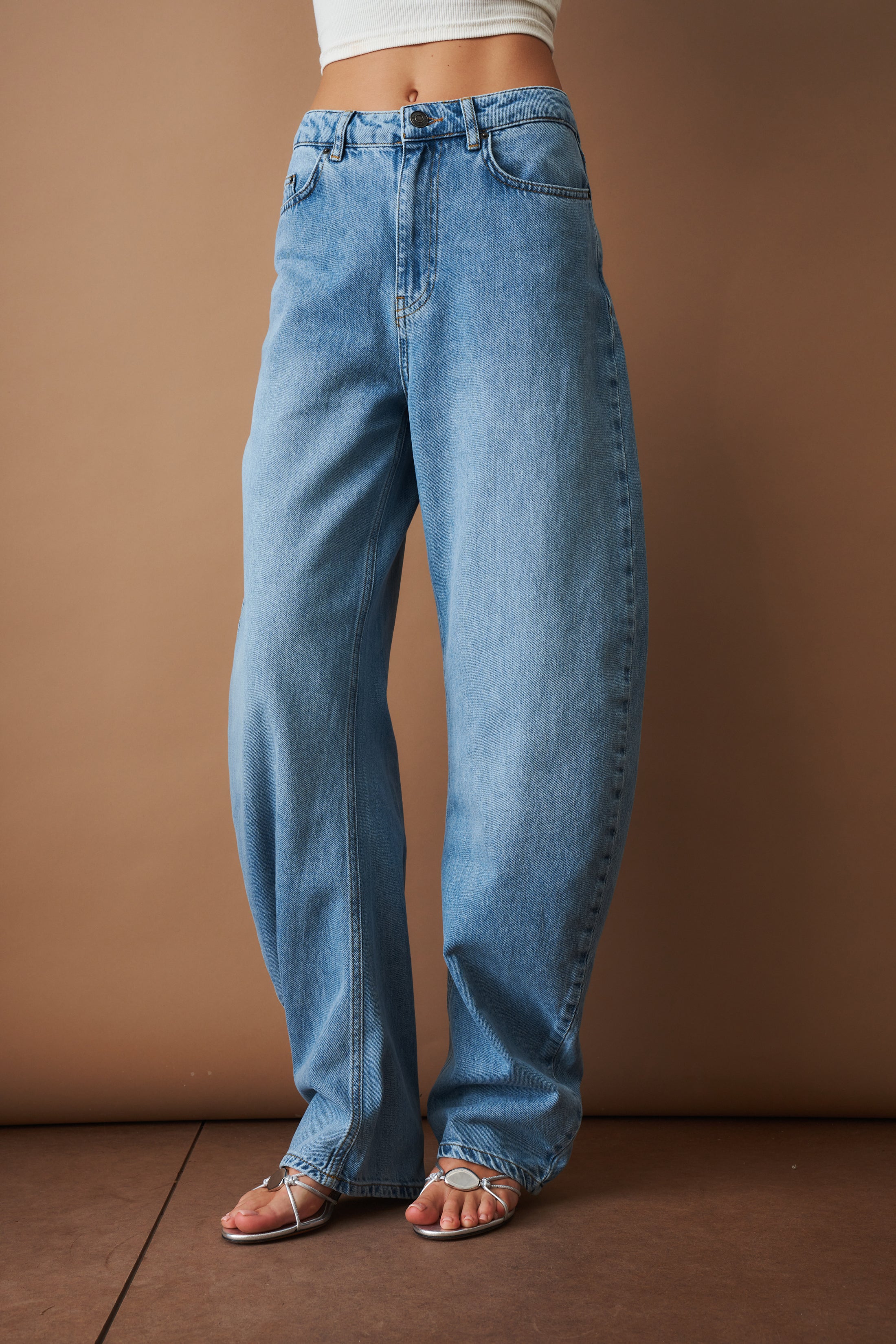 Rotate Draped Barrel Leg Jeans, stylish pants with draped design and barrel legs, shown in a natural denim finish.