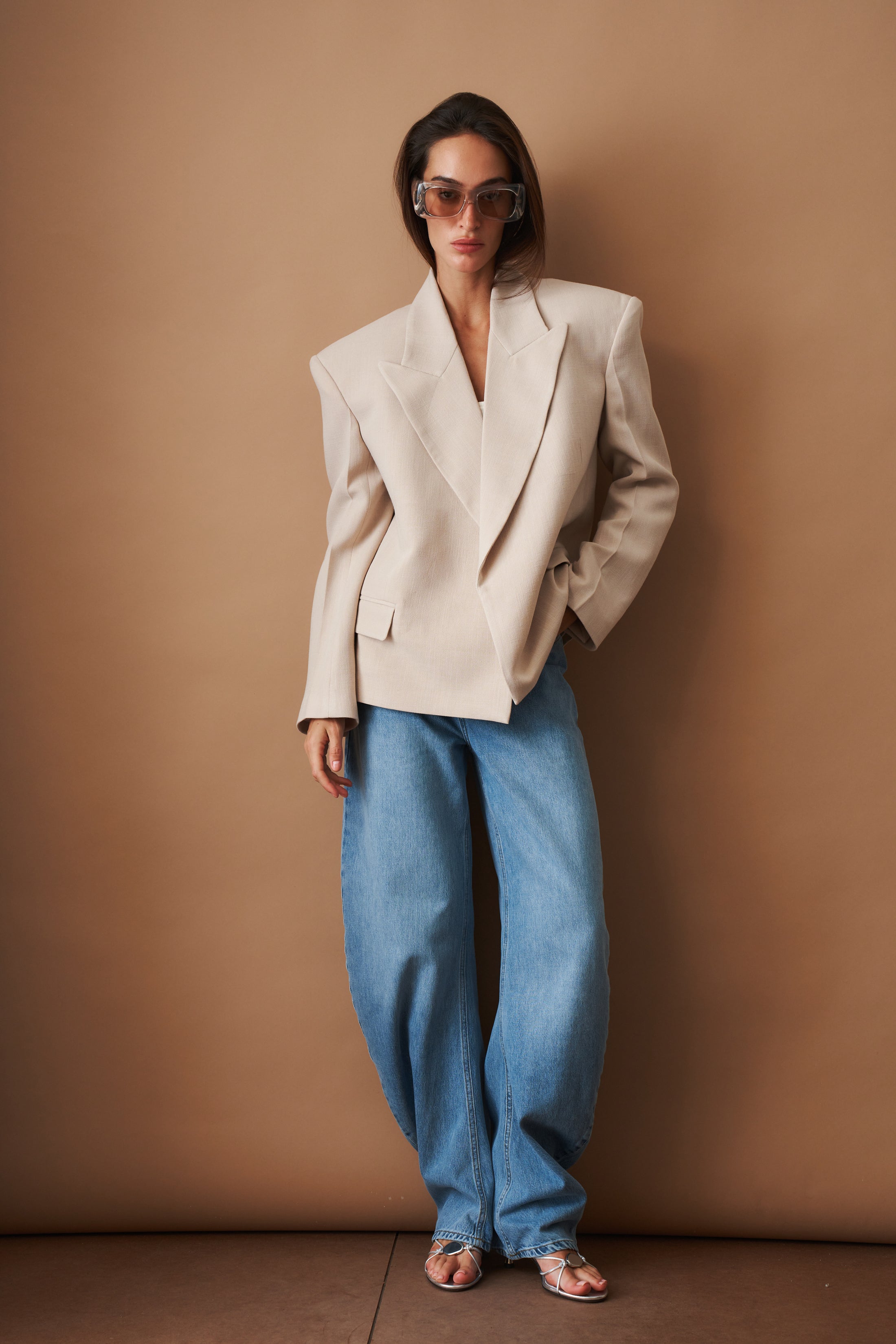 ROTATE Draped Barrel Leg Jeans pants featuring a relaxed fit with draped design and barrel legs, displayed on a hanger.