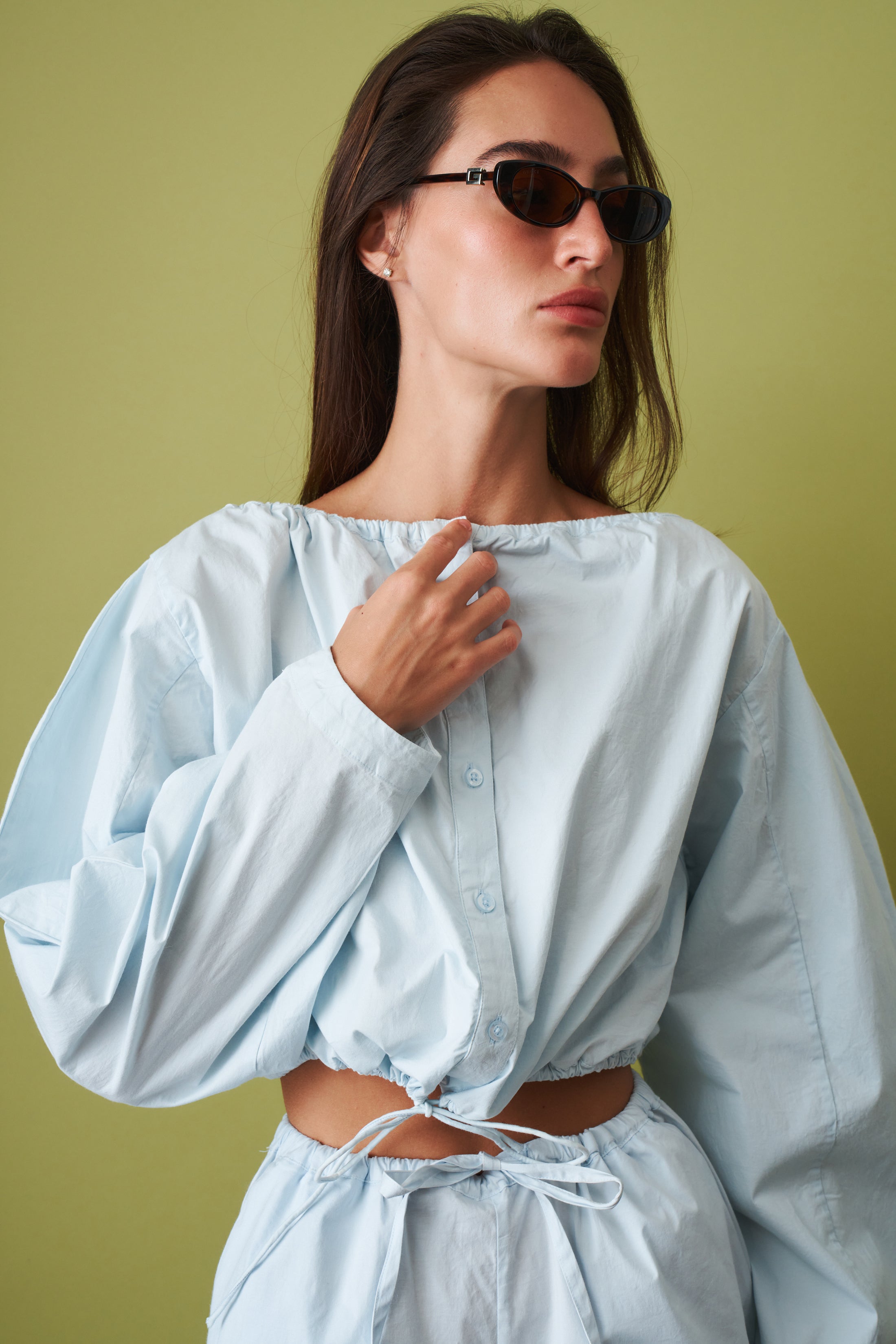Rotate Desordre tie strap long sleeve top featuring a fitted design, with a stylish tie detail at the waist and long sleeves.