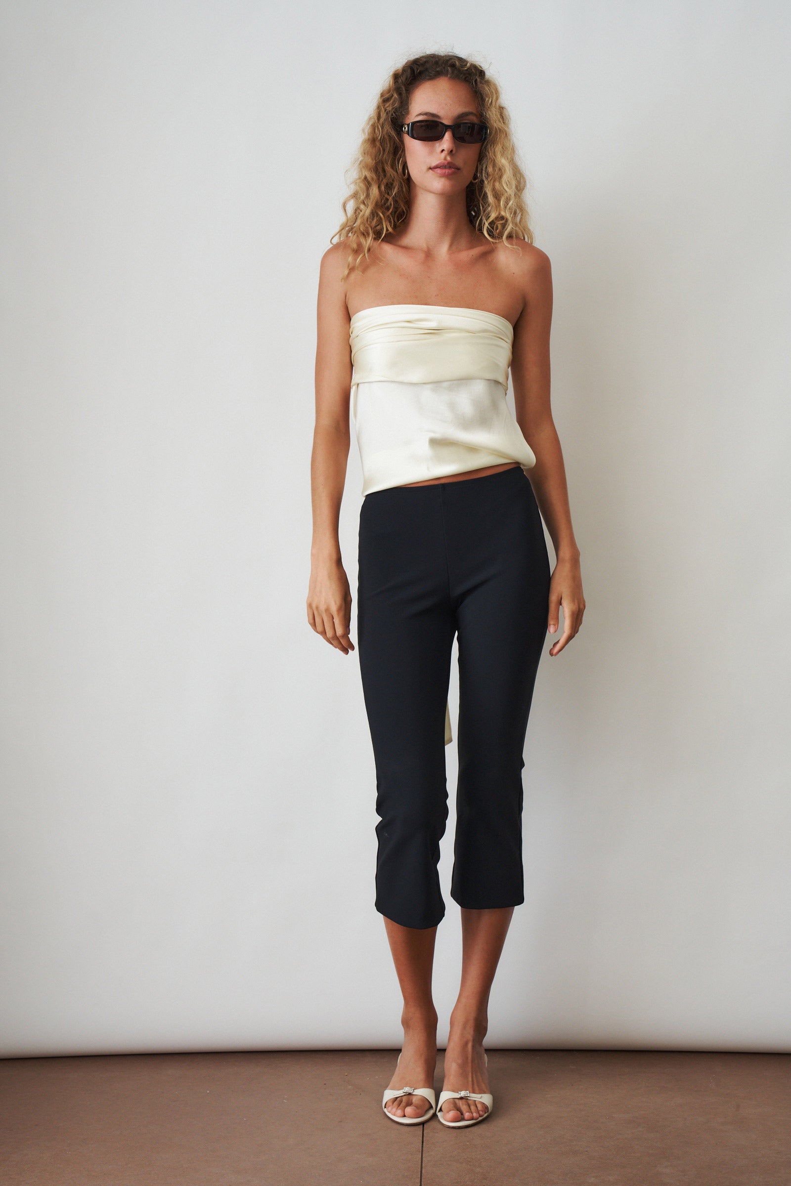 Ivory cowl neck halter top by ORSEUND IRIS, featuring a stylish draped neckline and sleeveless design for a chic look.