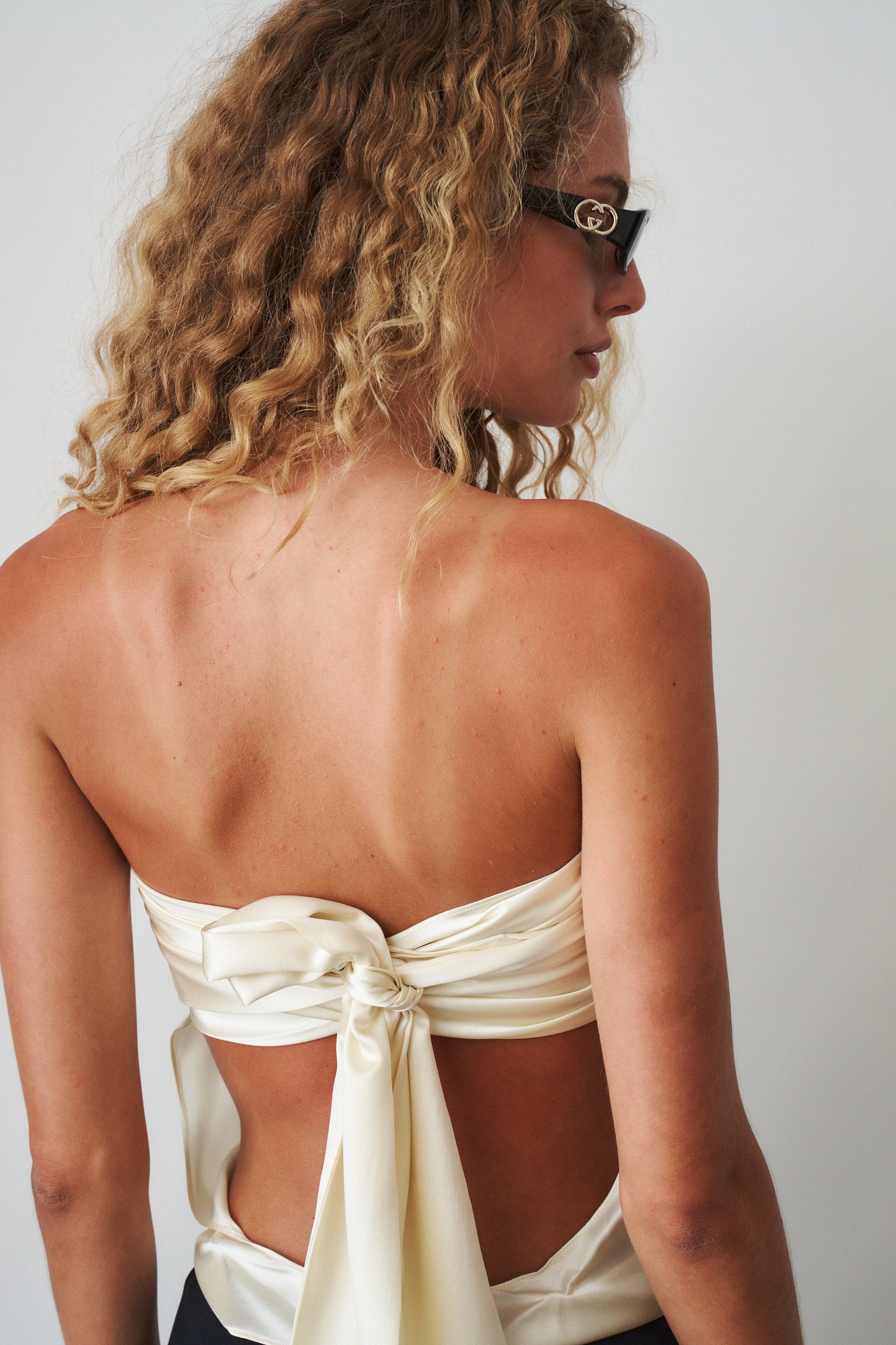 Ivory cowl neck halter top by ORSEUND IRIS, featuring a stylish draped neckline and sleeveless design.
