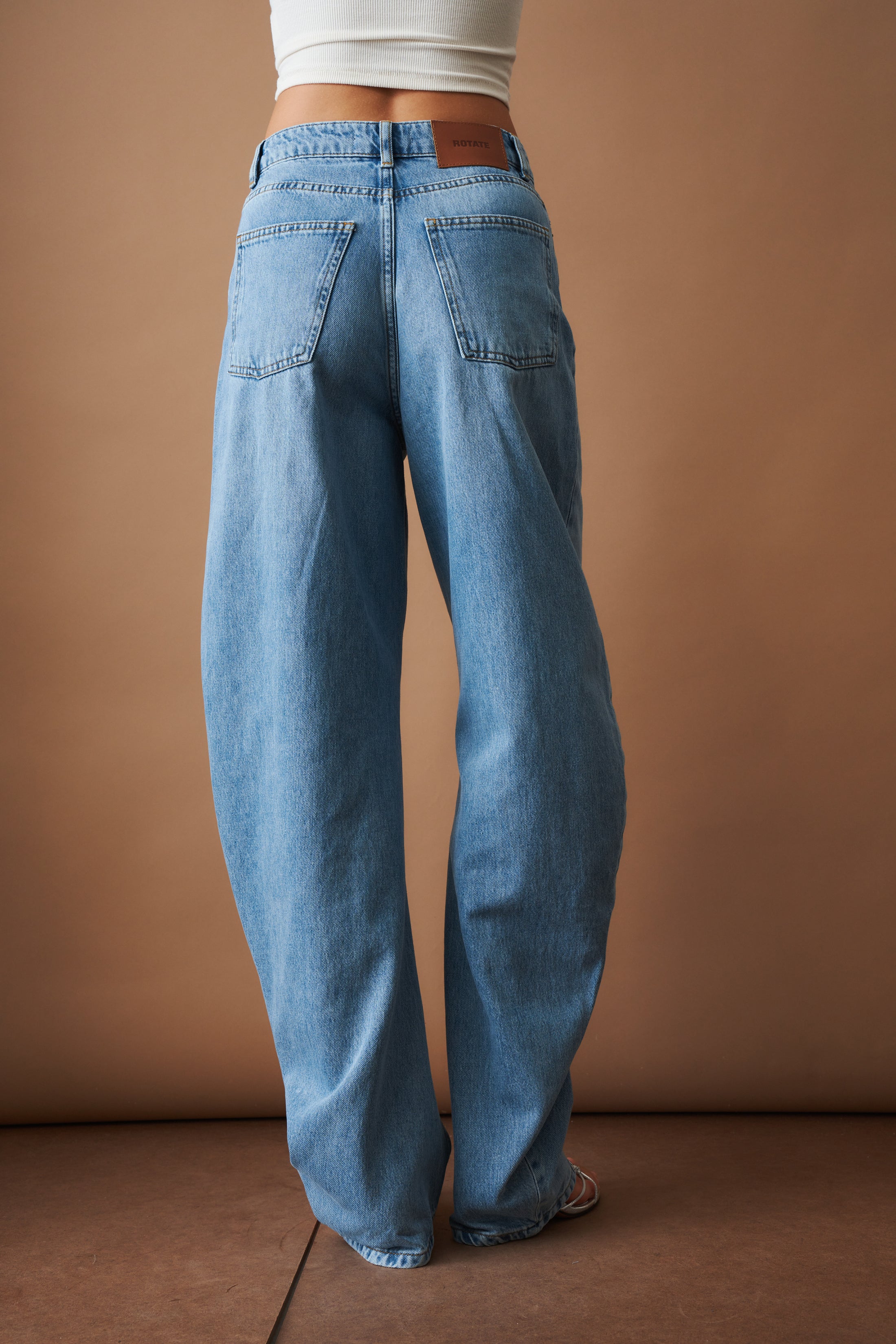Rotate Draped Barrel Leg Jeans, stylish denim pants with a relaxed fit and unique draped design, shown on a model.