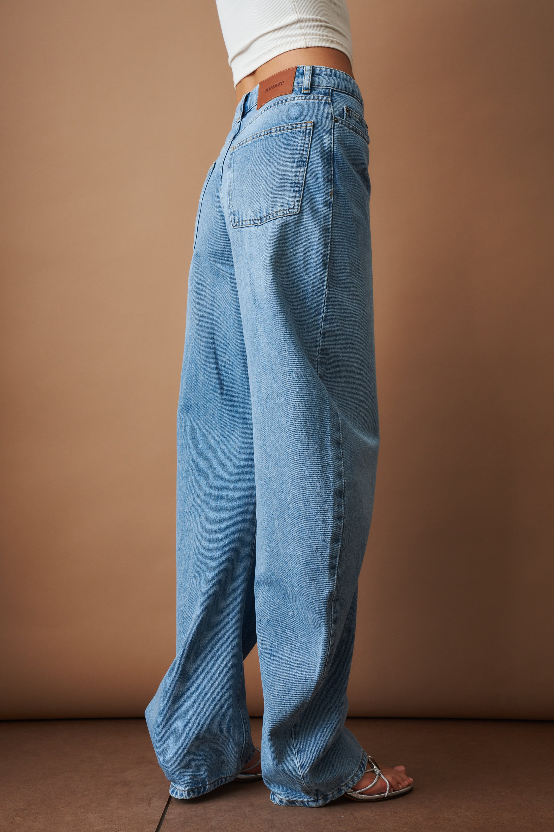 Rotate Draped Barrel Leg Jeans, stylish denim pants with a relaxed fit and draped design, shown in a natural pose.