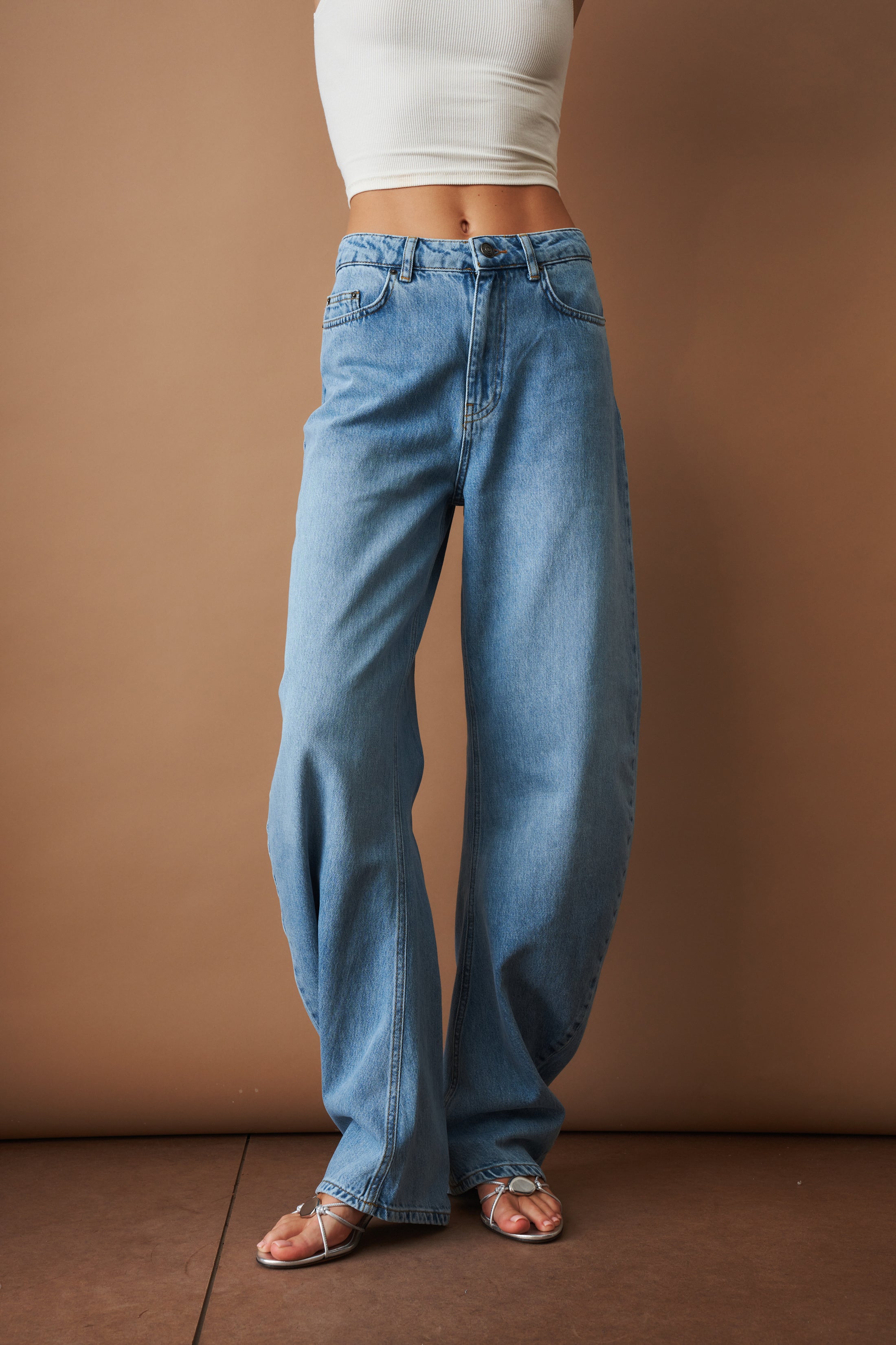 Rotate Draped Barrel Leg Jeans, stylish pants with a relaxed fit and draped design, shown on a model.