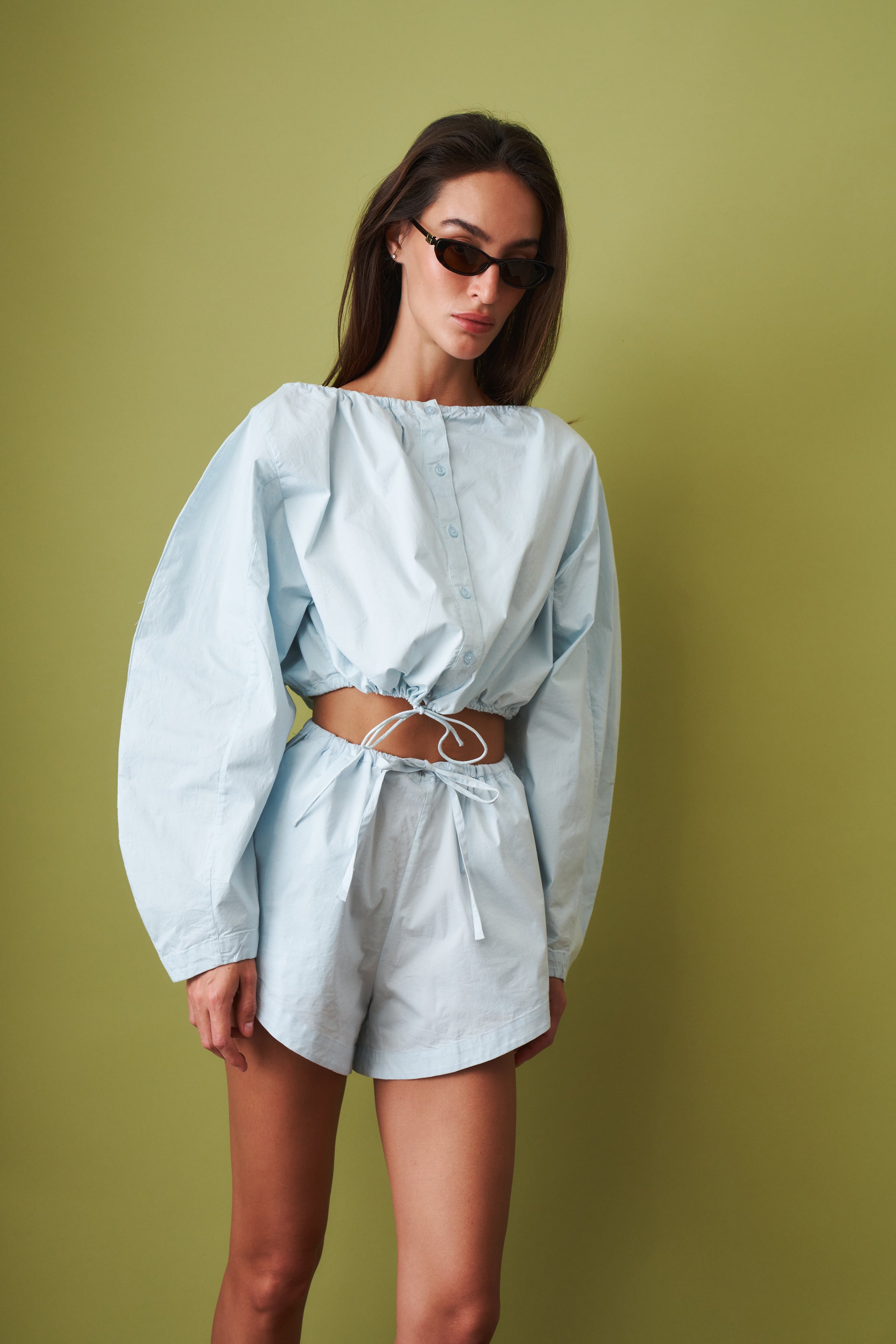 Rotate tie strap long sleeve top, beige color, with sleek design and tie details, shown on a model.